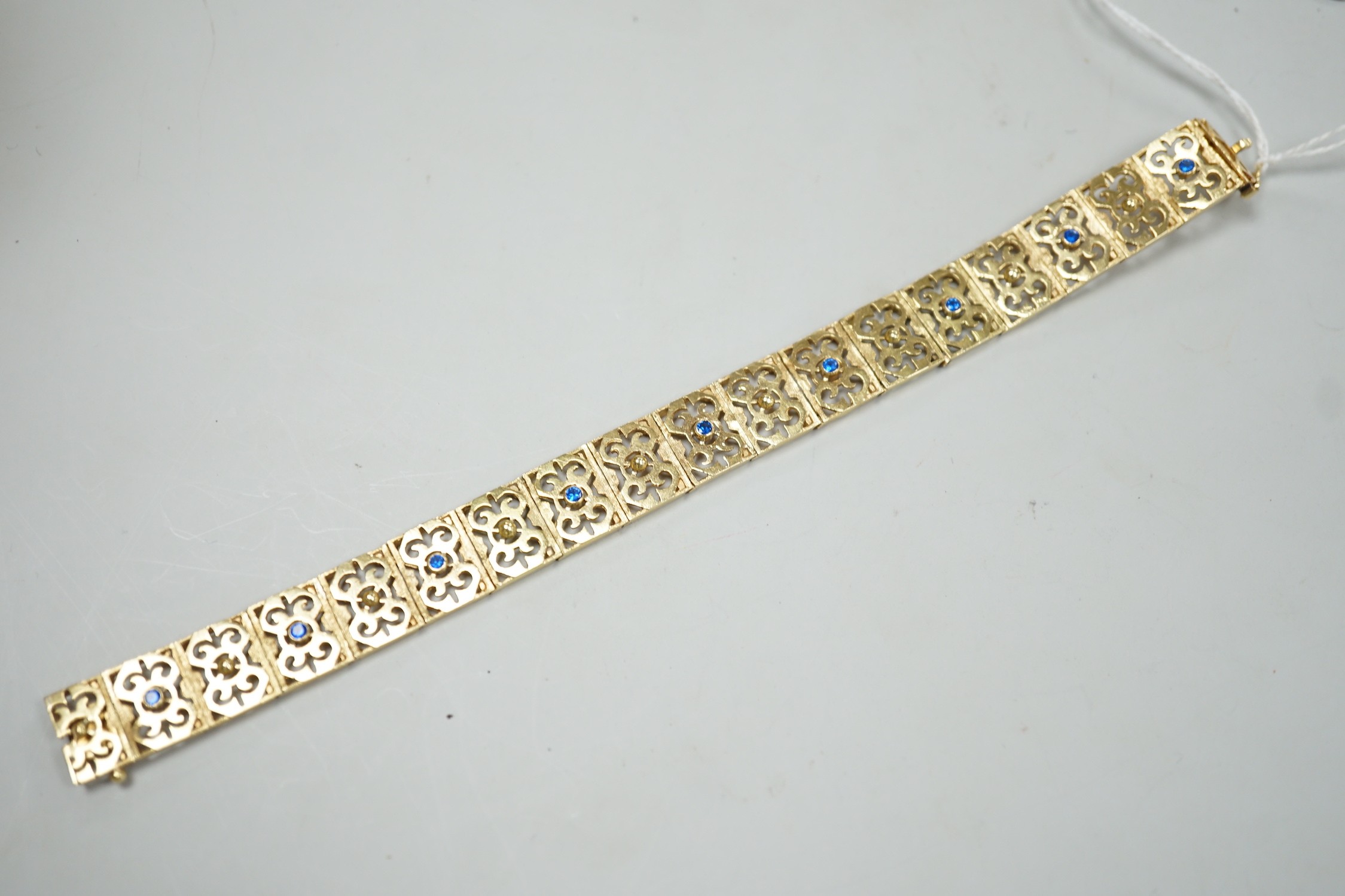 A modern pierced yellow metal and blue paste set bracelet, 19cm gross weight 28.2 grams.